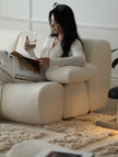Woman reading a magazine on a beige sofa in a cozy living room.