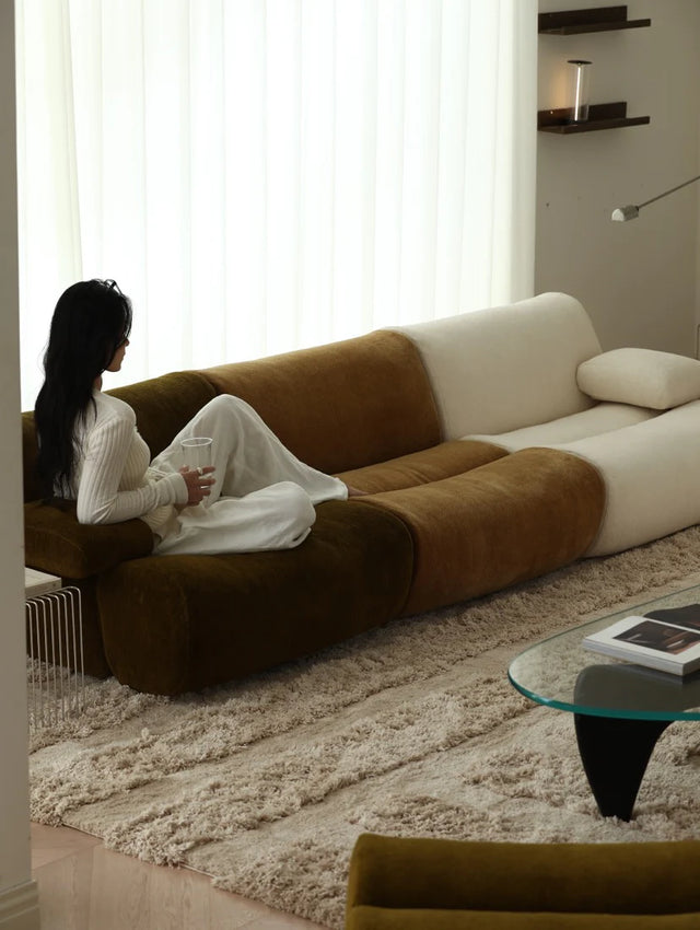 Woman sitting on a modern brown and white sofa in a well-lit room.