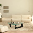 Modern living room with a beige sofa, glass coffee table, and decorative elements.