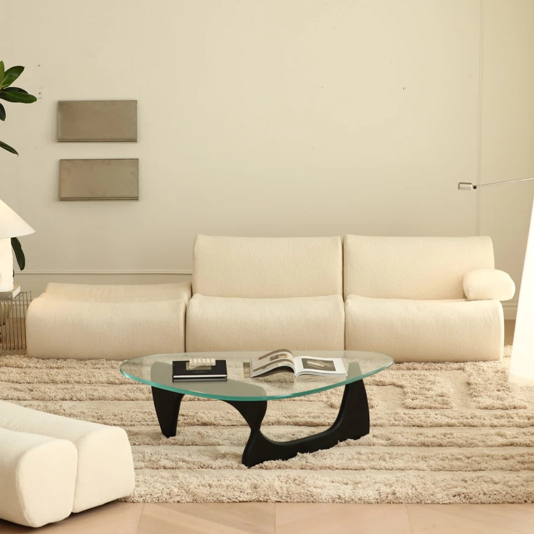 Modern living room with a beige sofa, glass coffee table, and decorative elements.