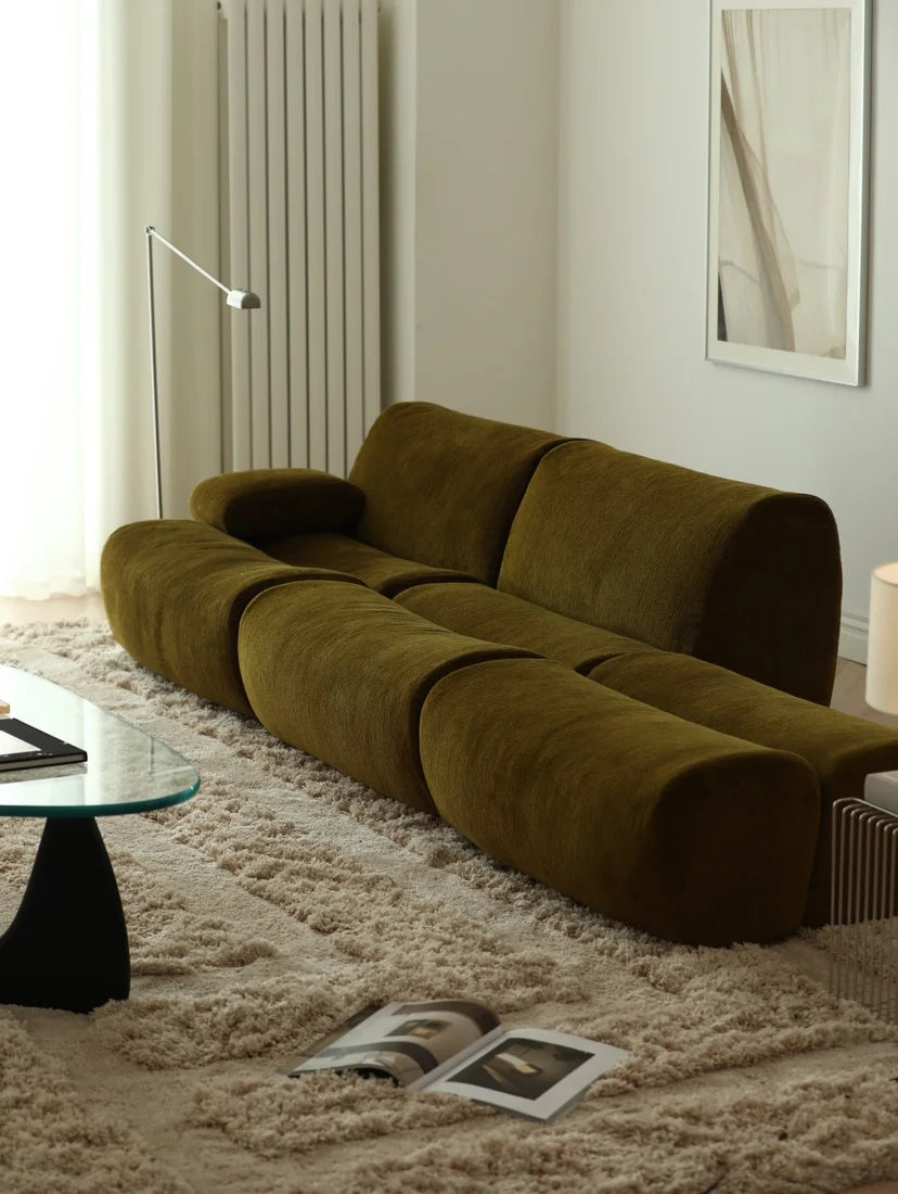Modern olive green sofa in a living room with a neutral color palette.