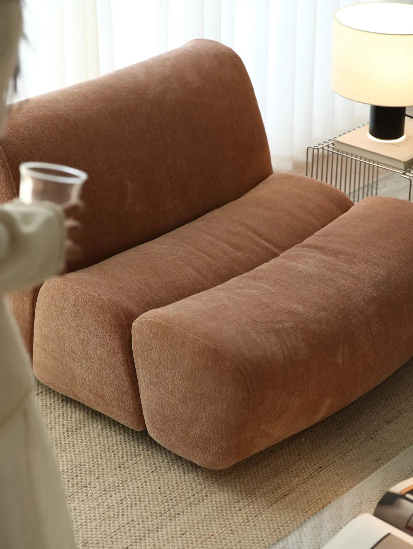 Brown sofa in a living room setting with a lamp and table.