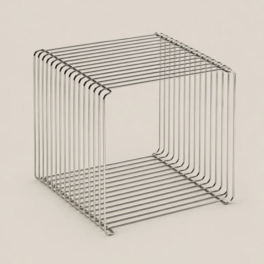 A minimalist, open-frame cube side table made of thin, polished metal wire with a brushed silver finish, set against a solid, warm off-white background.