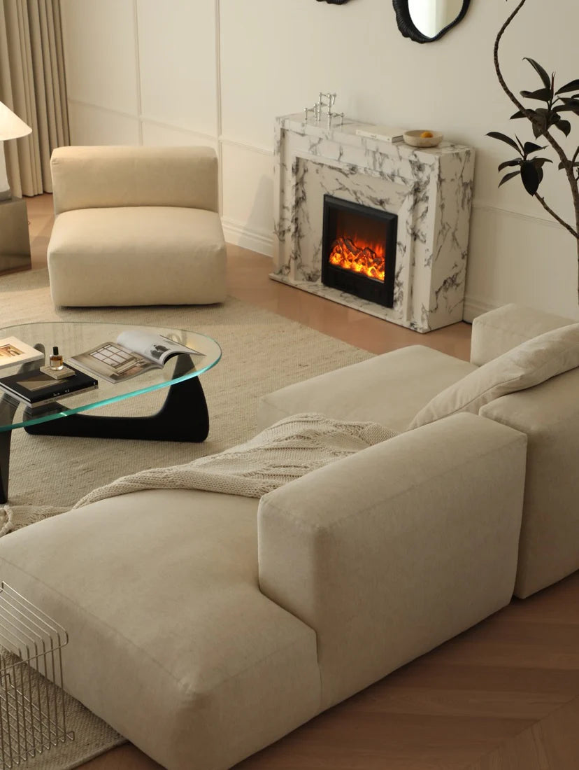 Modern living room with beige sofa, glass coffee table, and fireplace.