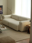 Beige sofa in a living room with a coffee table and lamp.
