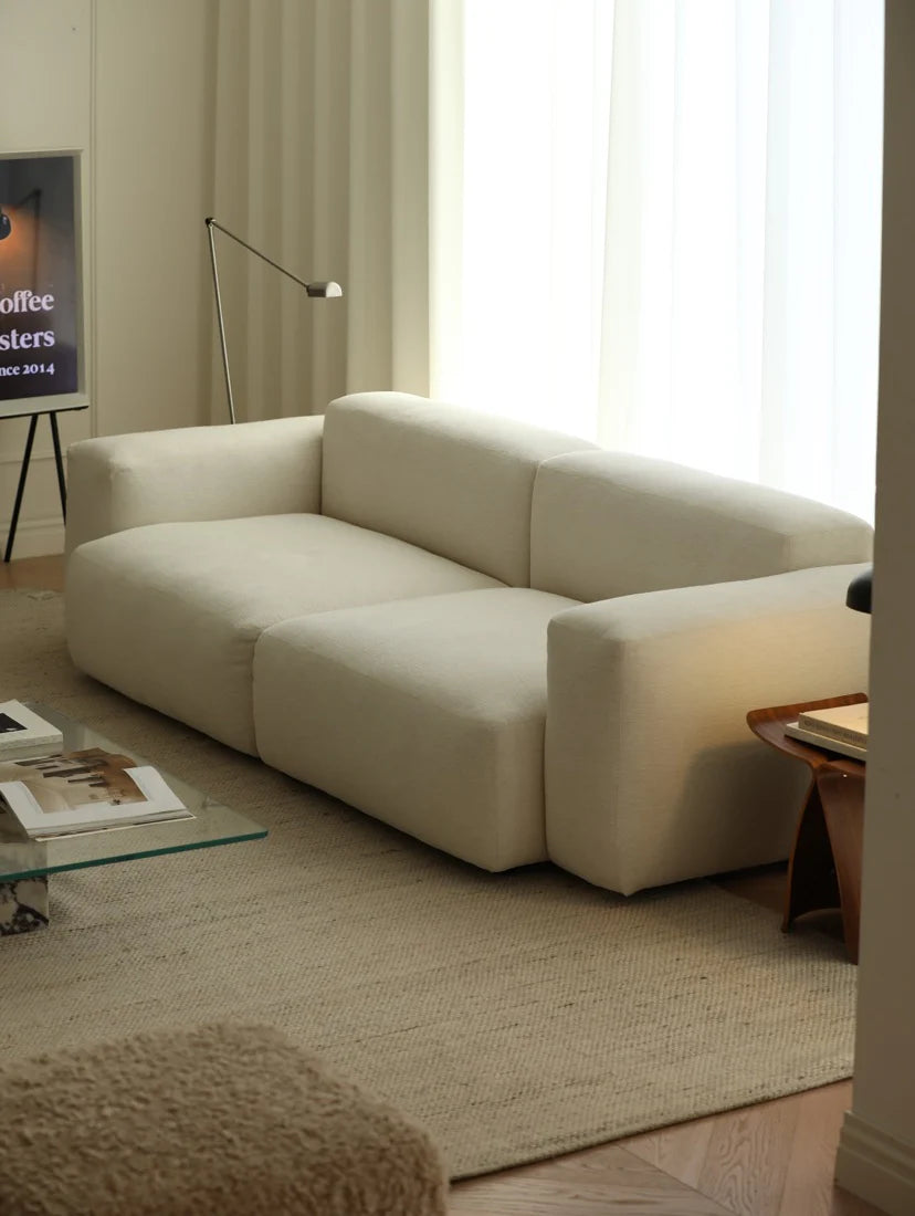 Beige sofa in a living room with a coffee table and lamp.