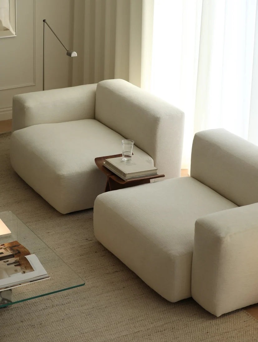 Modern beige sofa in a living room with a side table and glass of water.