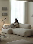 Woman sitting on a modern beige sofa in a minimalistic living room.