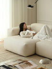 Woman reading a book on a beige sofa in a cozy living room.