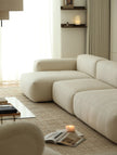 Modern living room with a beige sectional sofa, coffee table, and decorative items.