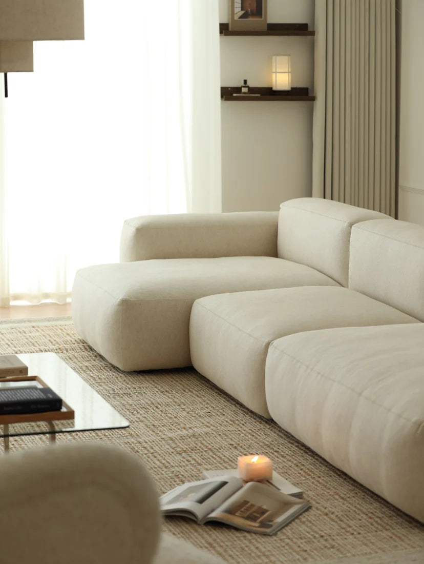 Modern living room with a beige sectional sofa, coffee table, and decorative items.