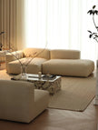 Modern living room with beige sectional sofa and marble coffee table.