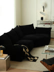 Black sectional sofa in a modern living room with a checkered blanket.
