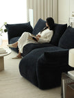 Woman sitting on a dark blue sofa in a modern living room.