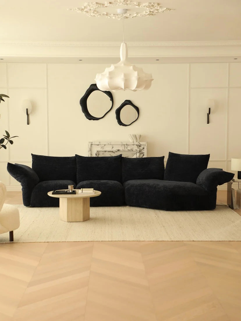Modern living room with a black sectional sofa, marble coffee table, and decorative wall art.