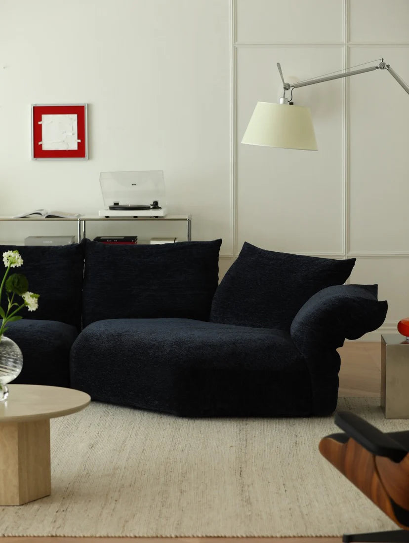 Modern living room with a dark blue sofa, light-colored walls, and minimal decor.