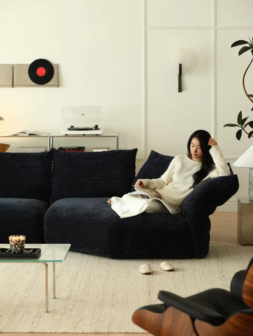 Woman sitting on a dark blue sofa in a modern living room.