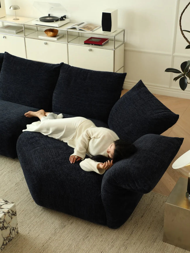 Child lying on a dark blue sofa in a modern living room.