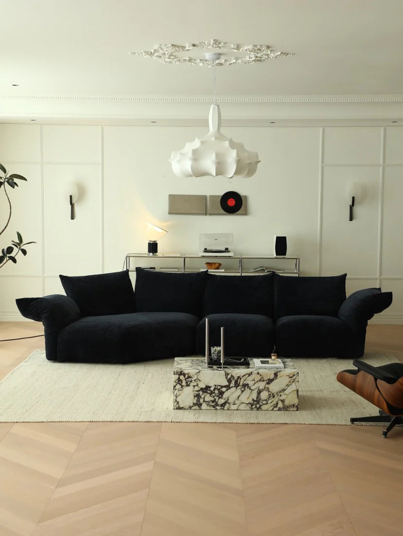Modern living room with a black sofa, marble coffee table, and decorative wall art.