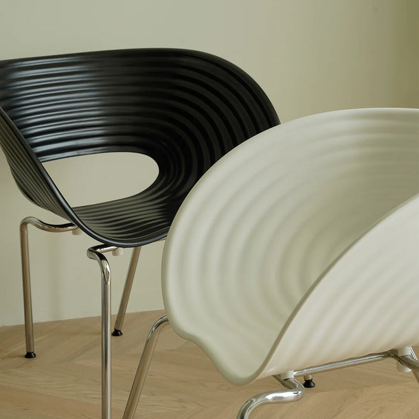 Two modern chairs, one black and one white, on a wooden floor with a neutral background.