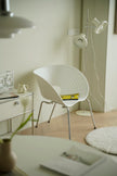 Modern interior with a white chair, desk, and floor lamp in a minimalistic setting.